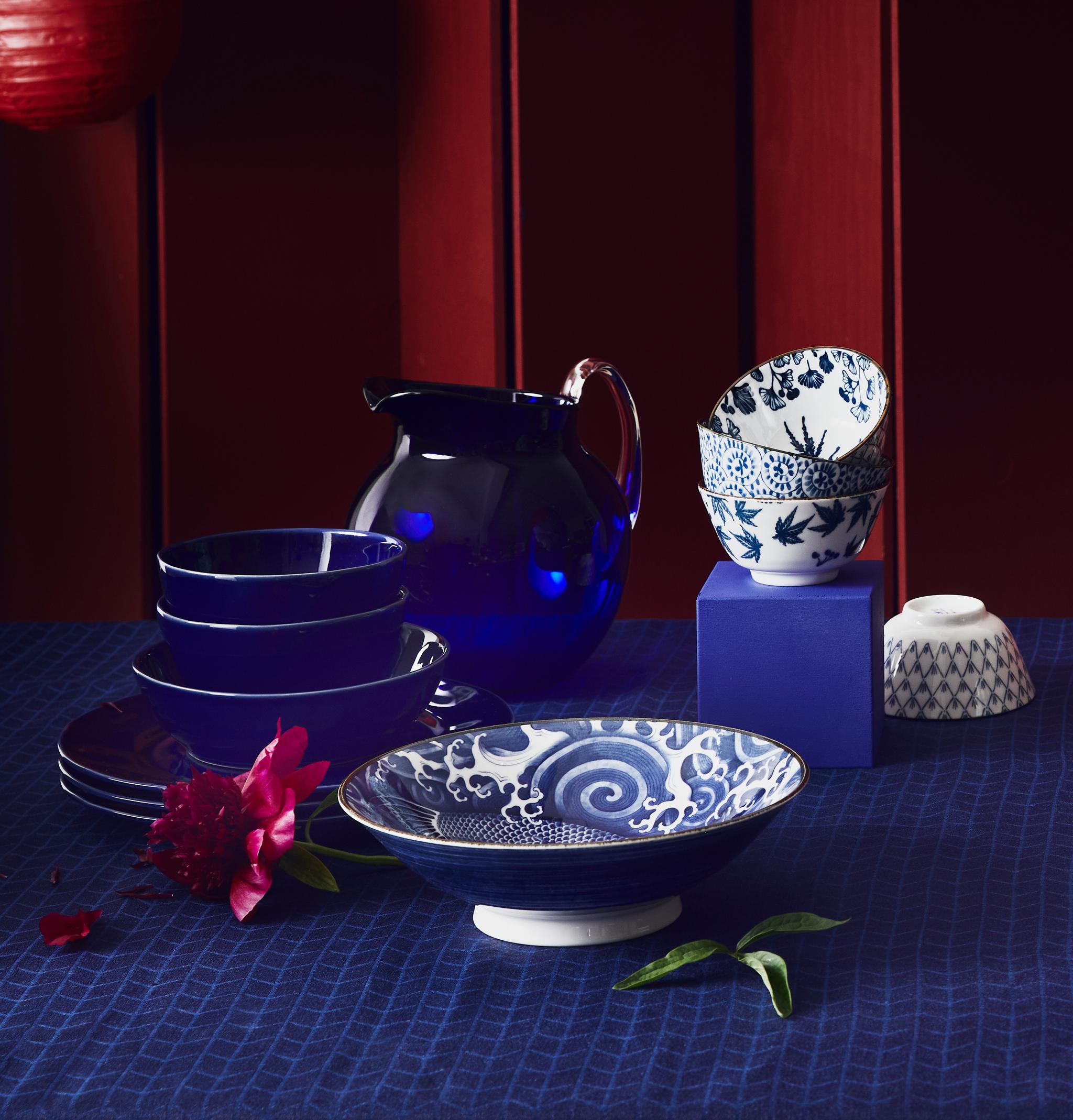 Blått og hvitt servise på blå duk med rød omgivelser