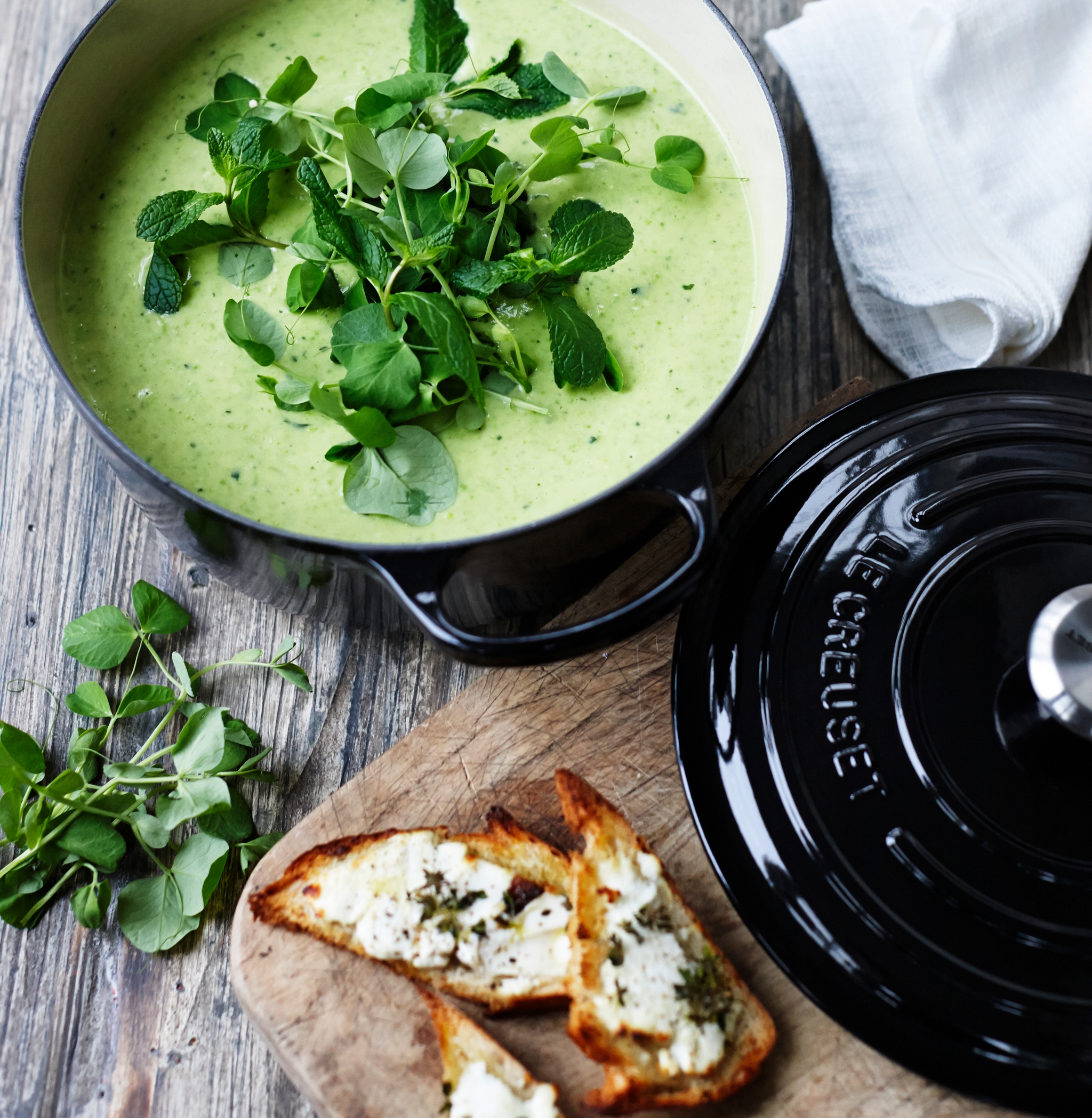 Le creuset svart gryte med grønn suppe i på spisebord