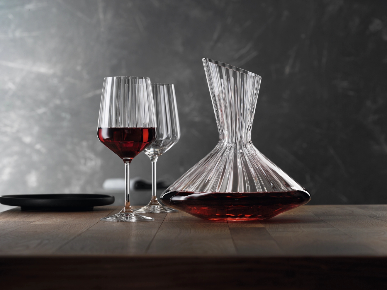 Spiegelau vinglas med ett mörkt rött vin i och en vinkaraff på bord