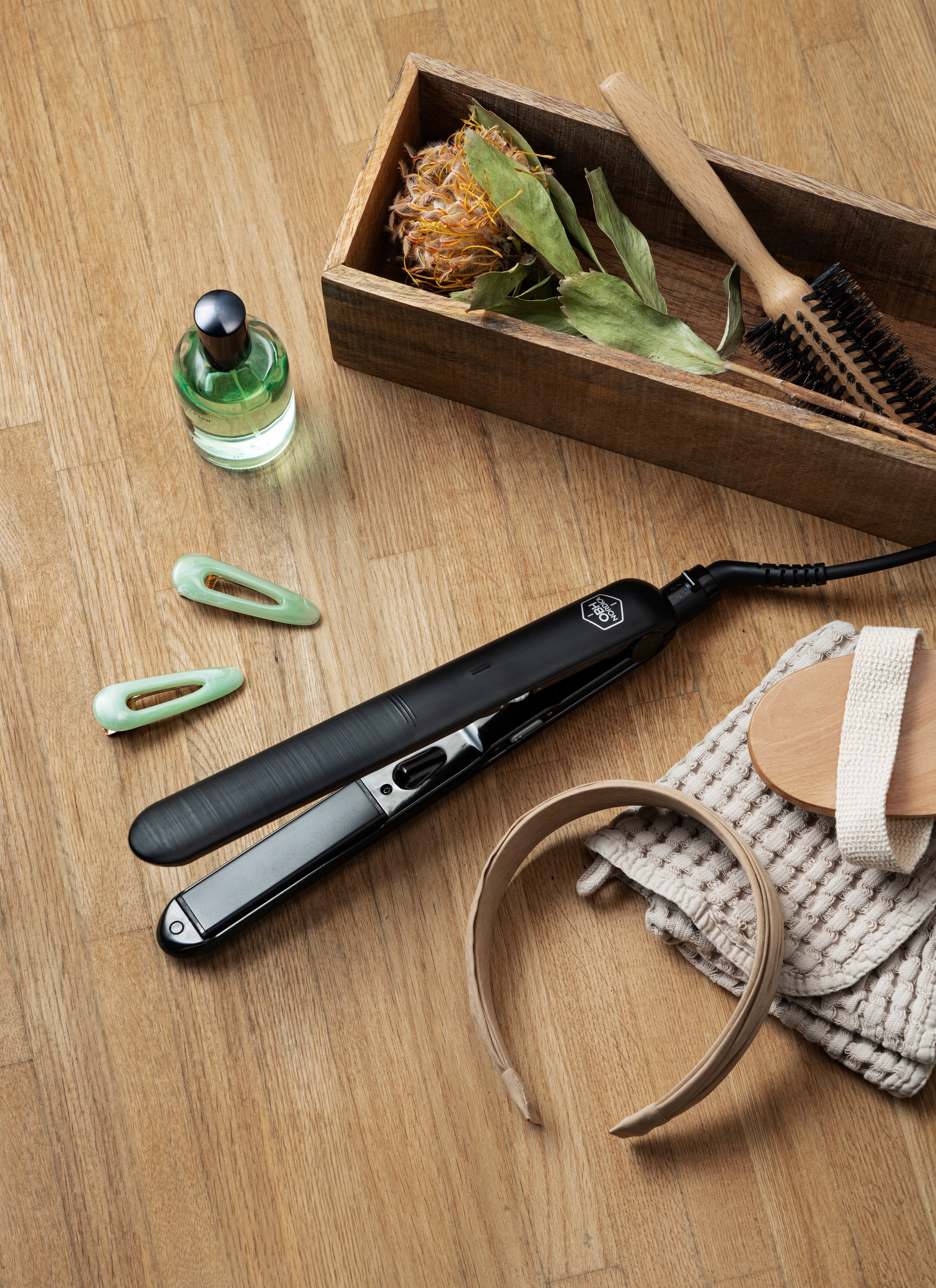 en hårplattång ligger på ett träbord bredvid en parfymflaska