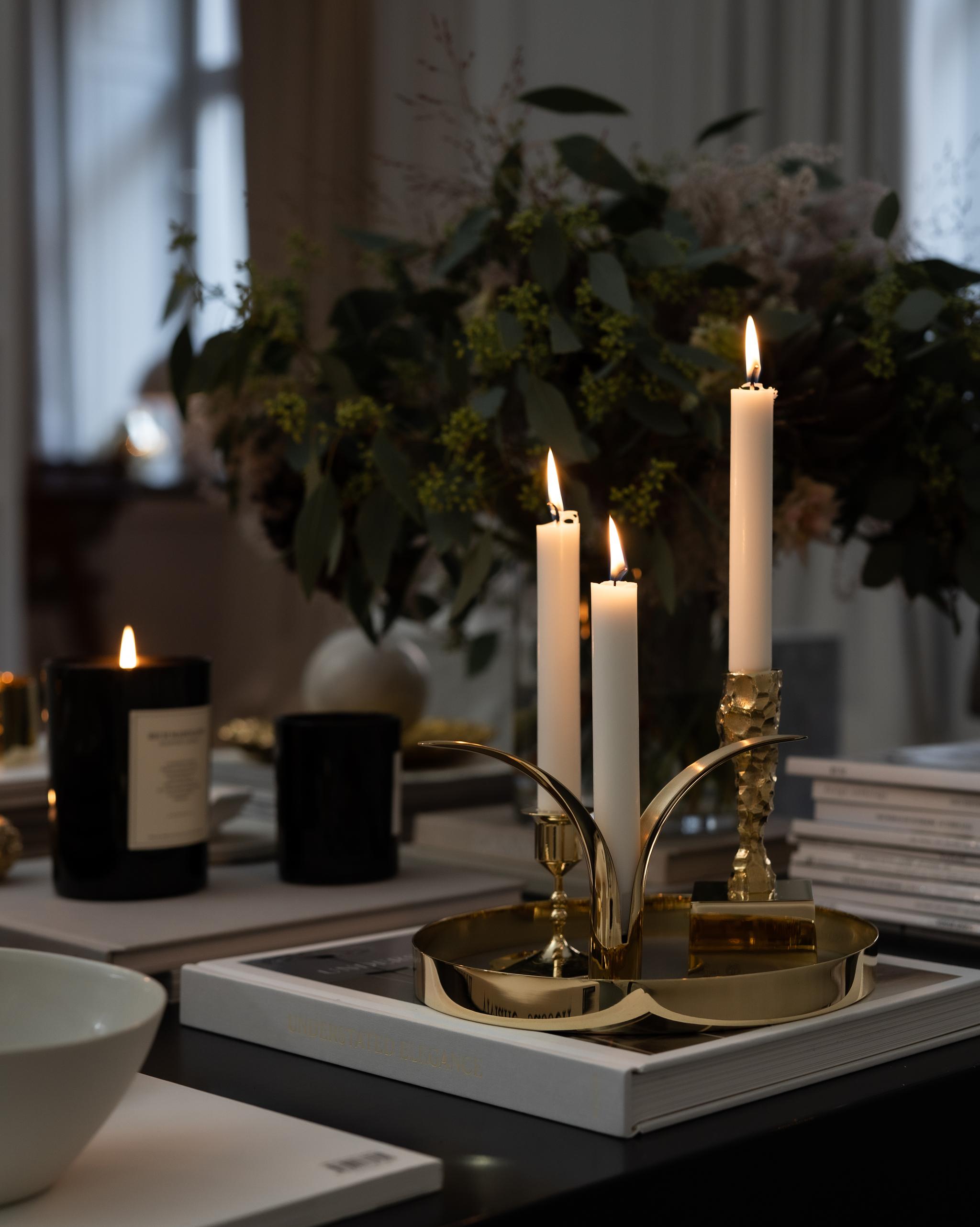 Tända ljus i mässingljusstakar från Skultuna står på ett marmorbord