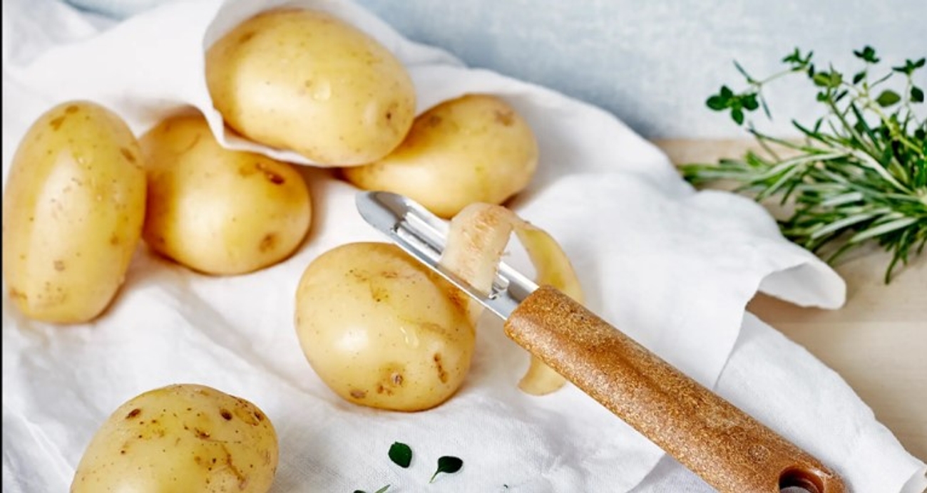 Potatisskalare på vit kökshandduk med lite grönt på sidan 