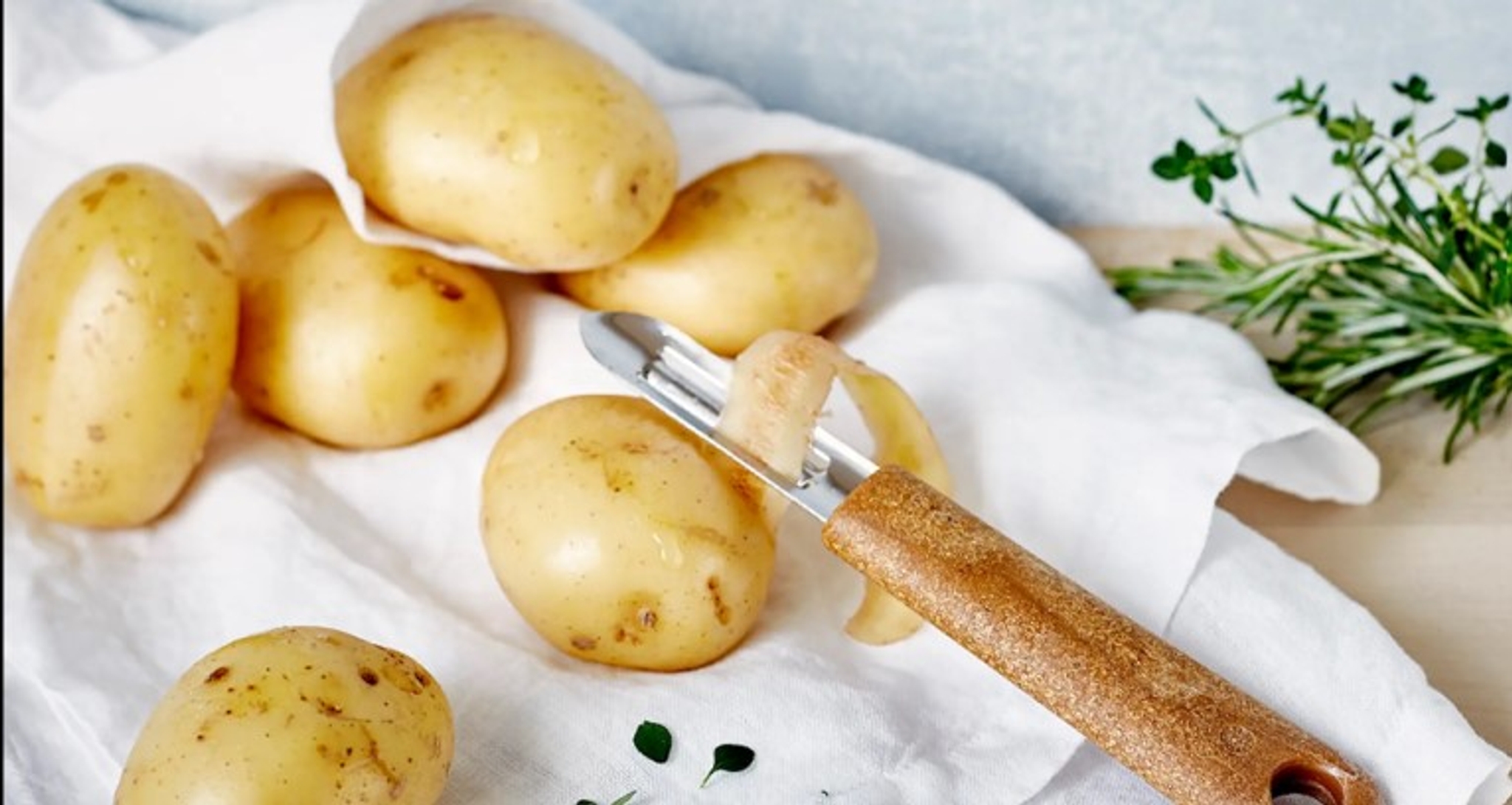 Potatisskalare på vit kökshandduk med lite grönt på sidan 