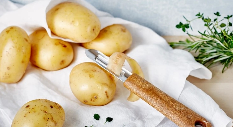Potatisskalare på vit kökshandduk med lite grönt på sidan