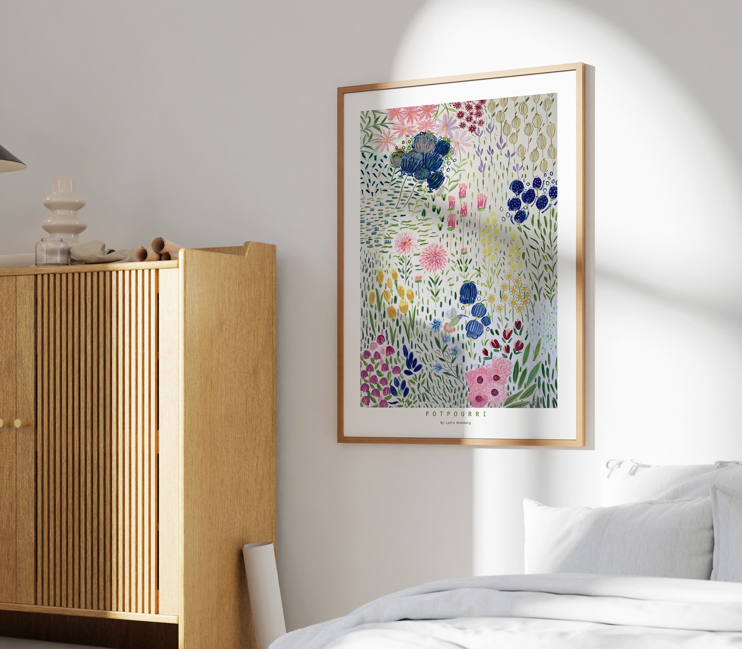 Ett inramat tryck av färgglada vildblommor hänger på en vit vägg i ett ljust sovrum.