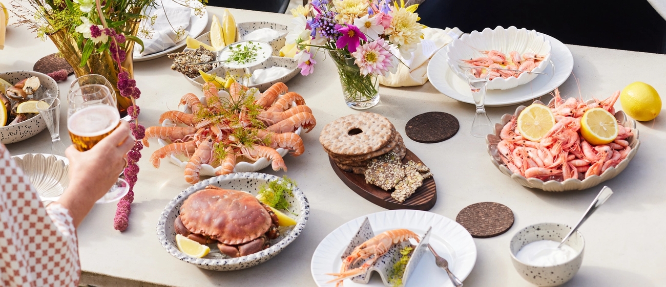 Äyriäisbuffet katettu pöytä täynnä katkarapuja ja lisukkeita kukkien kera