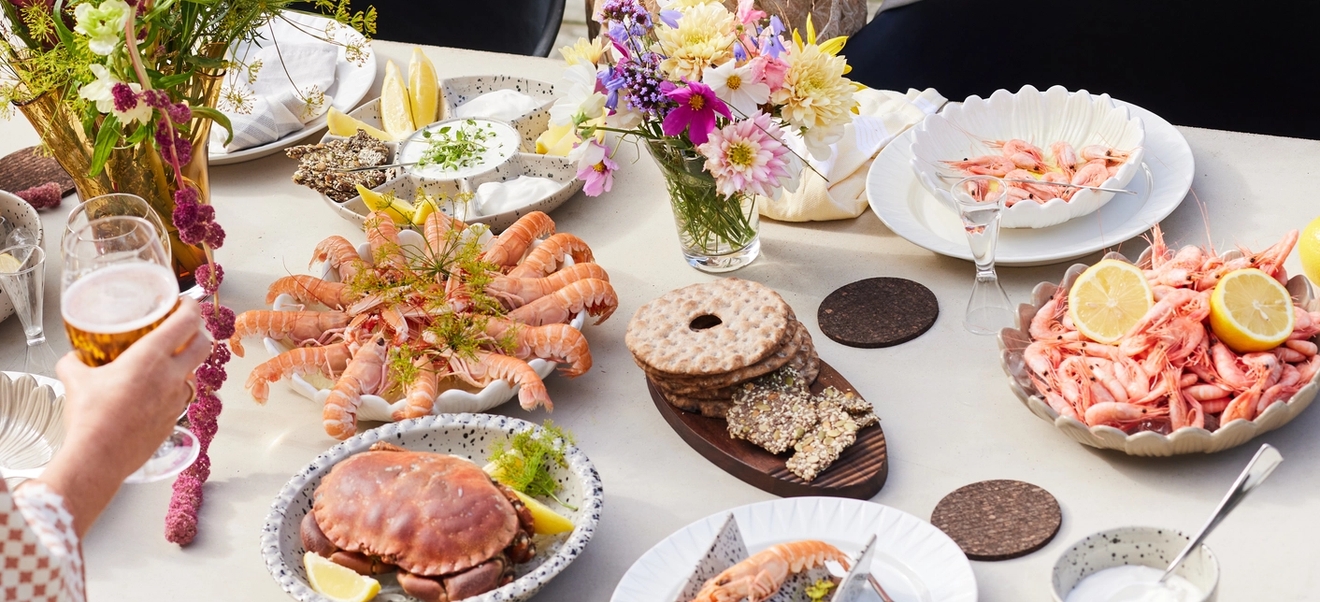 Äyriäisbuffet katettu pöytä täynnä katkarapuja ja lisukkeita kukkien kera