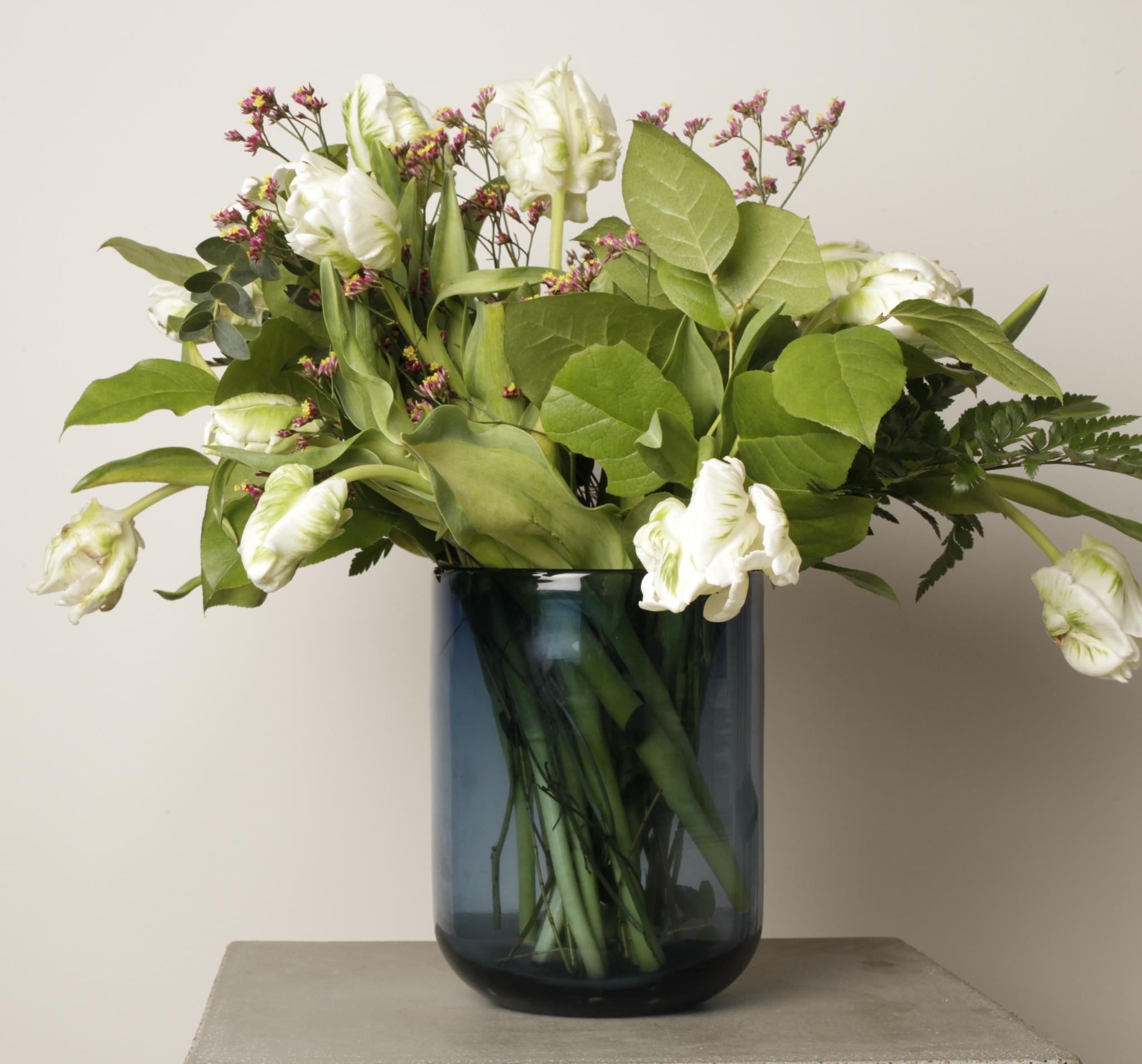 Sininen lasimaljakko ison kukkakimpun kera