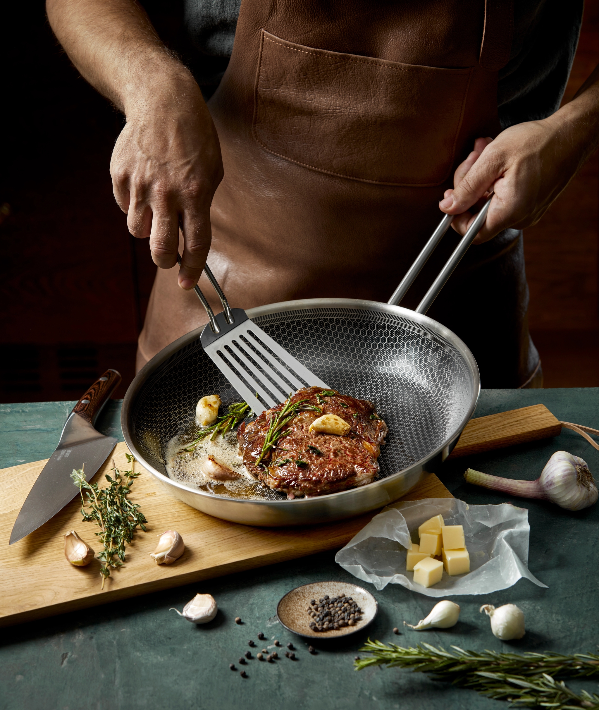 mies paistaa pihviä paistinpannulla lastalla