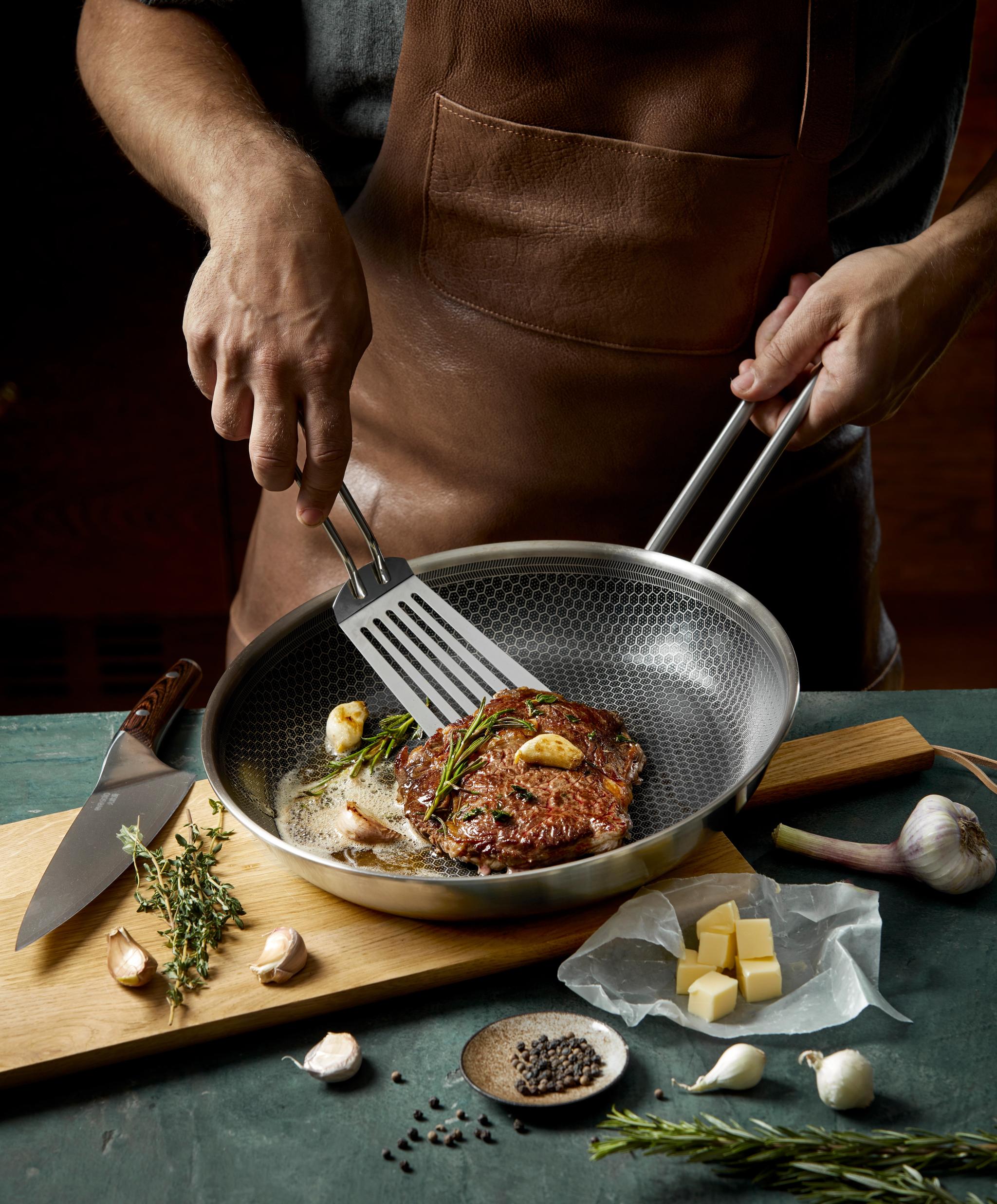 mies paistaa pihviä paistinpannulla lastalla