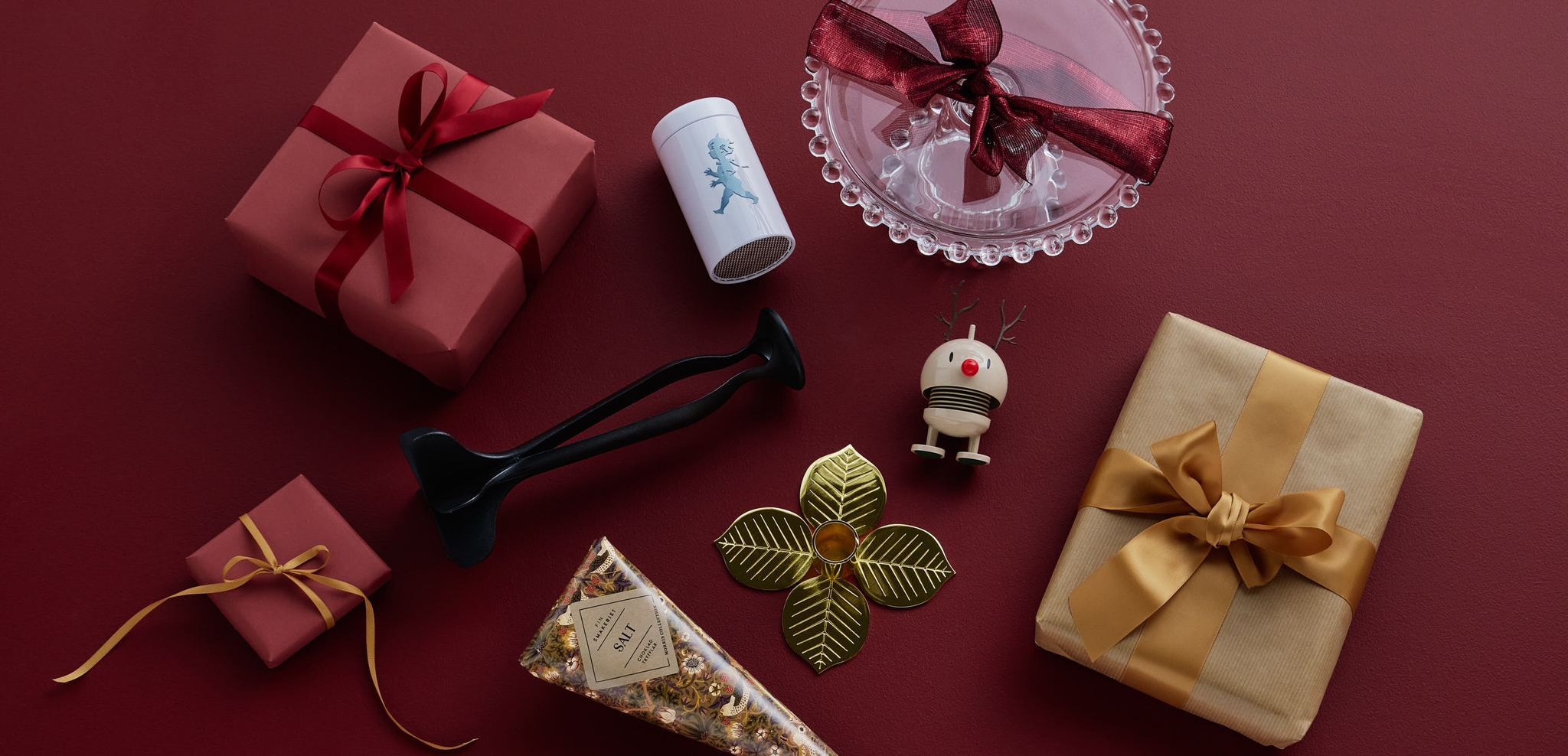 A collection of red and gold gift boxes, a glass dish, and various decorative items on a dark red background.
