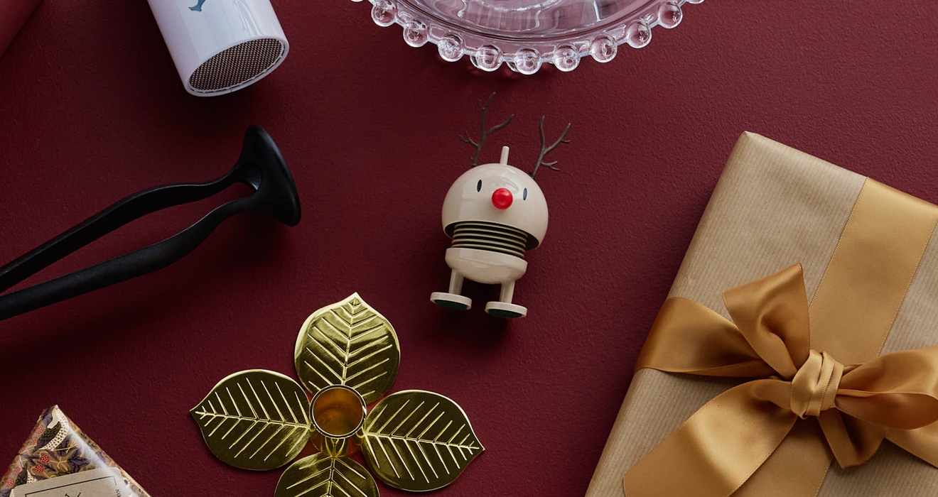 Olika inslagna presenter och små dekorativa föremål arrangerade på en djupröd yta.