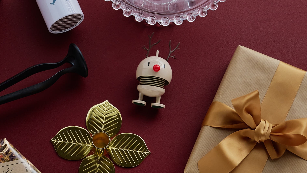 A collection of red and gold gift boxes, a glass dish, and various decorative items on a dark red background.