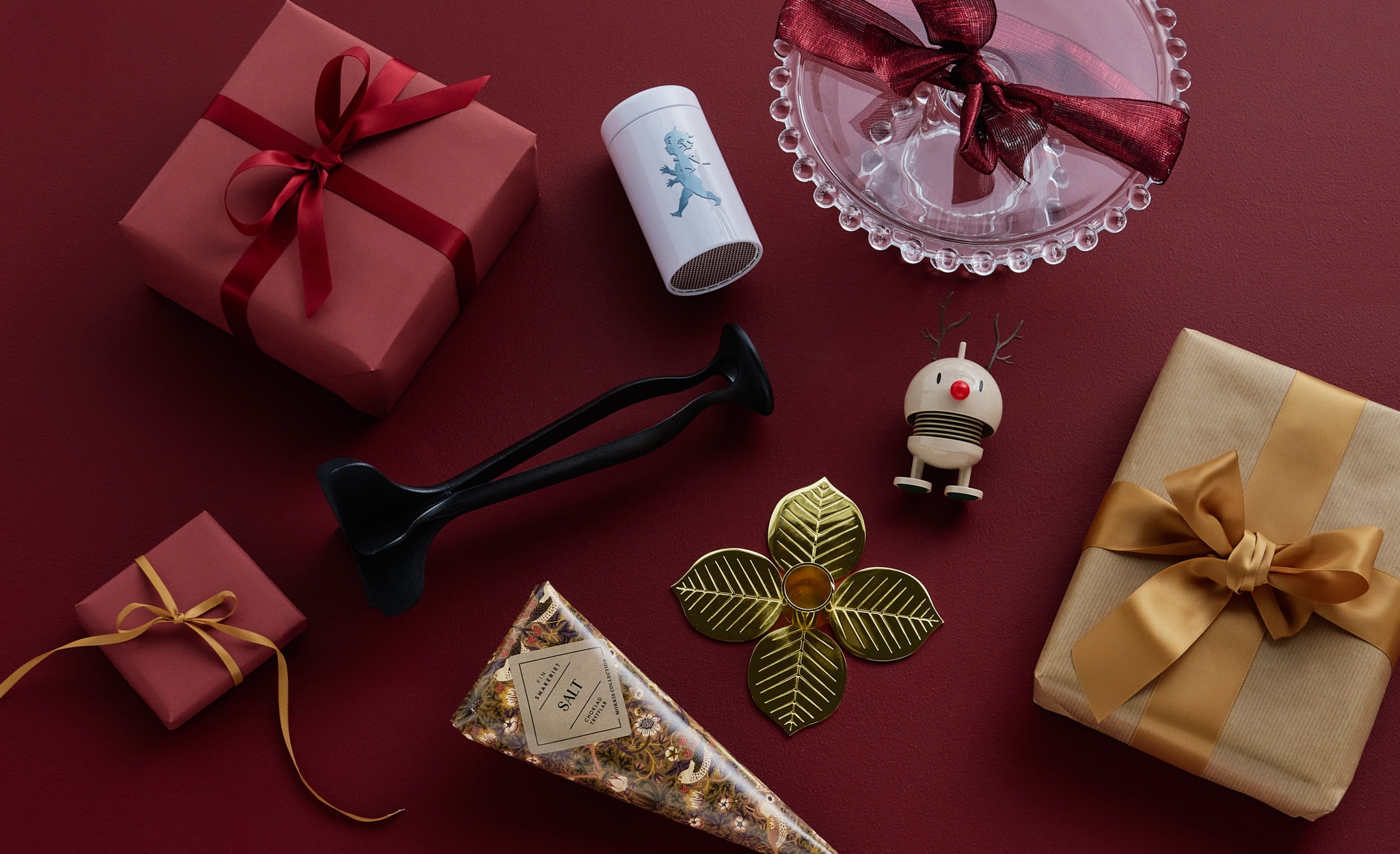 An assortment of festive gifts and decorative objects on a red background.