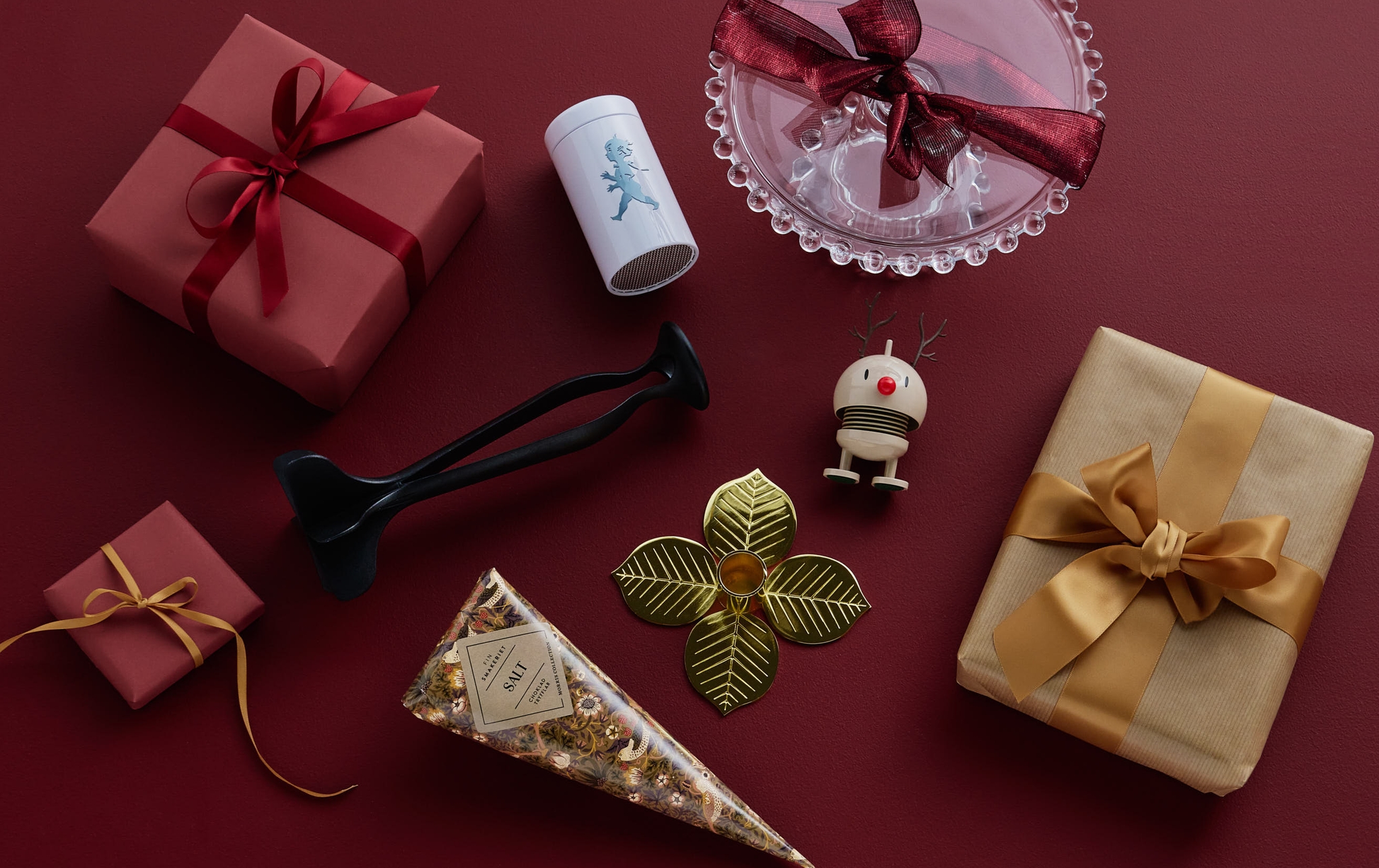 Olika inslagna presenter och juldekorationer mot en röd bakgrund.