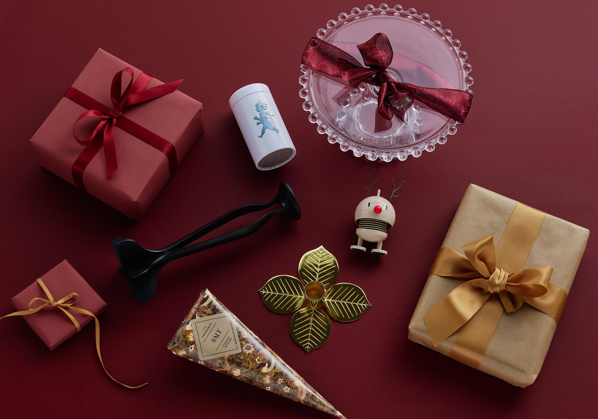 Olika inslagna presenter och juldekorationer mot en röd bakgrund.