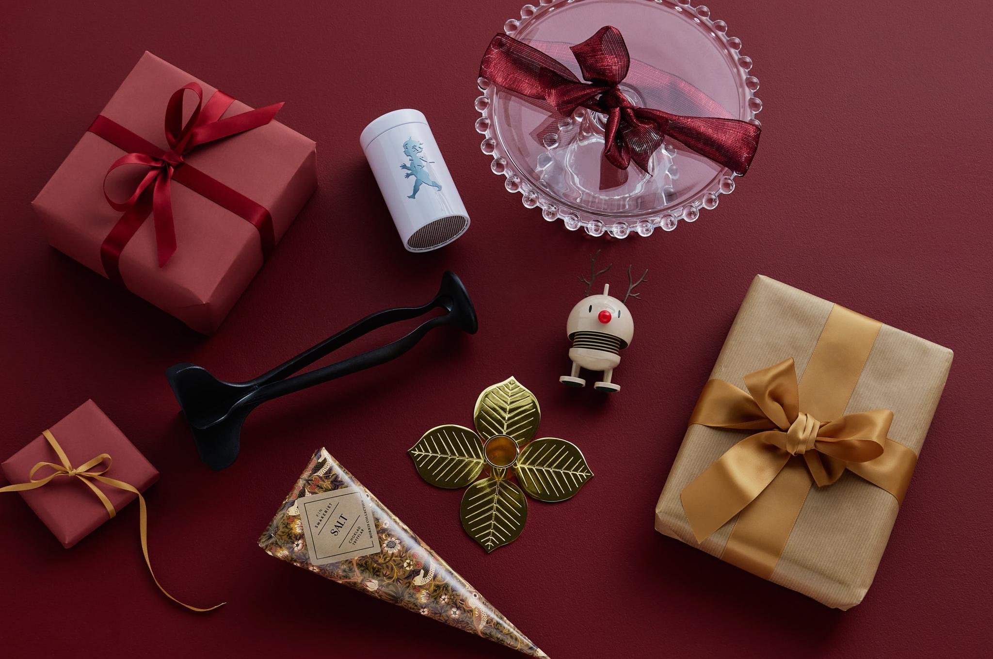 A collection of red and gold gift boxes, a glass dish, and various decorative items on a dark red background.