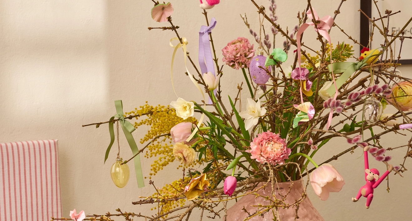 Pajunoksat ja pääsiäiskoristeet vaaleanpunaisessa maljakossa