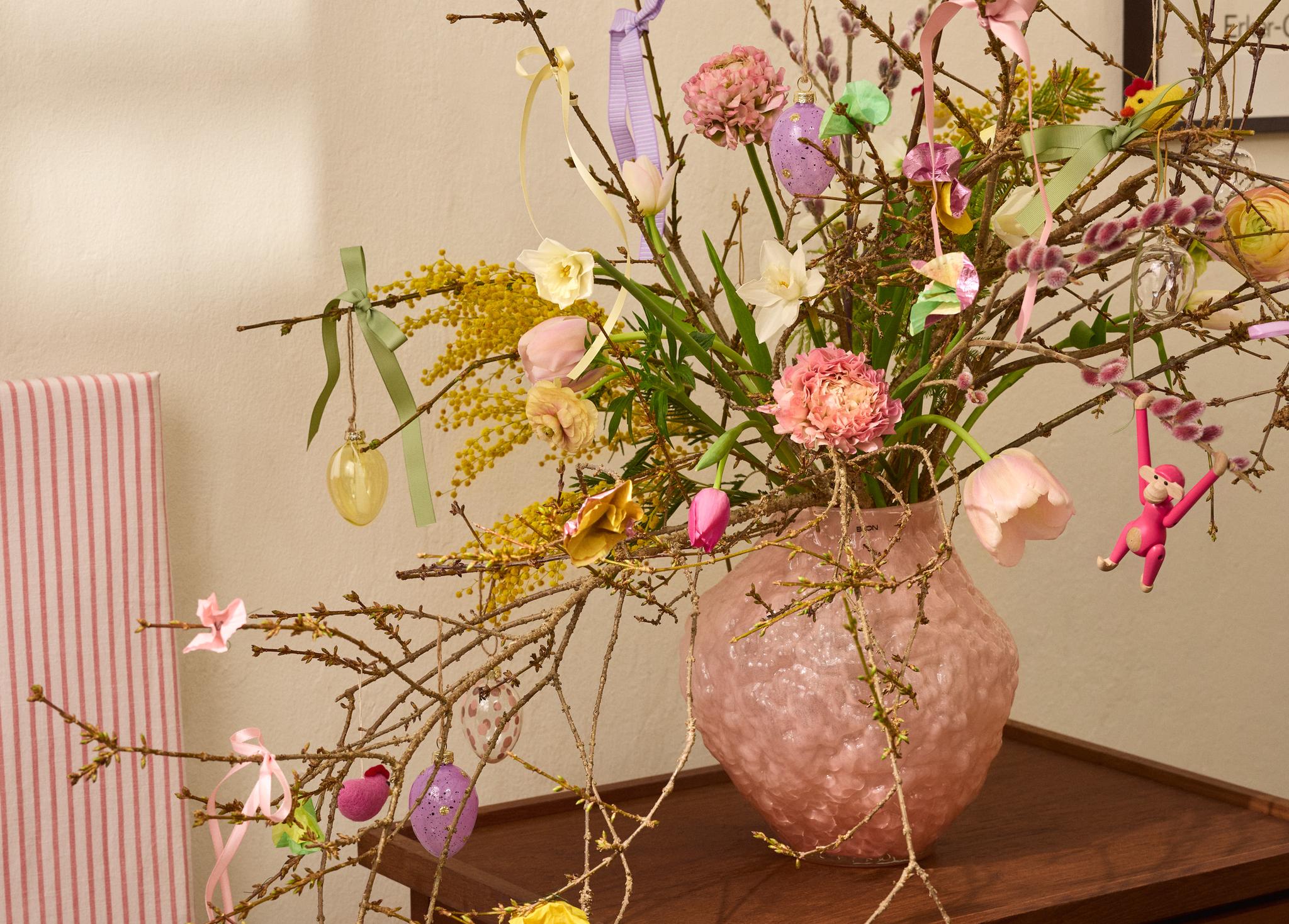 Påskris med dekorationer i en rosa vas