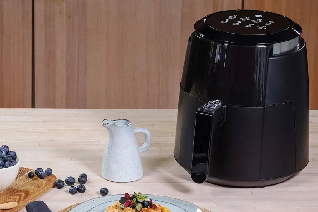 Musta wilfa airfryer ja makea piirakka mustikoiden kera vaaleansinisellä lautasella