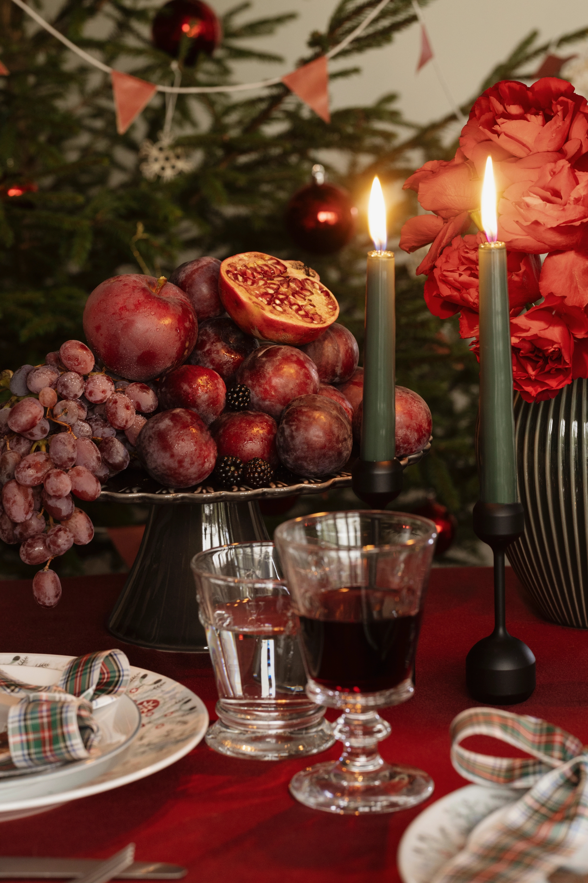 a table set for a christmas dinner with fruit and candles
