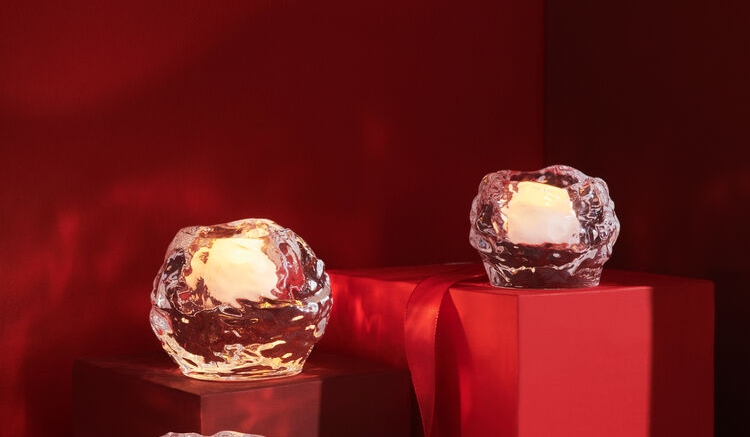 Tre Snowball-ljuslyktor i isliknande glas med tända värmeljus på röda och rosa sockel