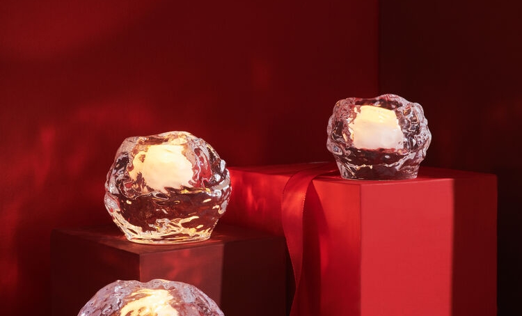 Tre Snowball-ljuslyktor i isliknande glas med tända värmeljus på röda och rosa sockel