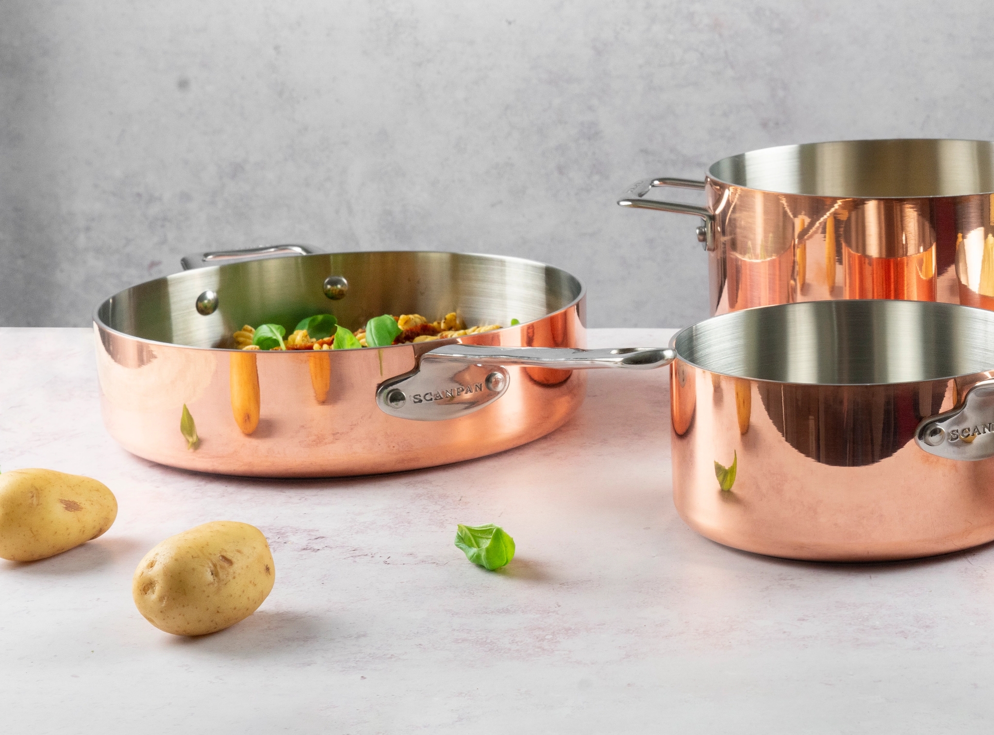 kopparstekpannor på marmorskiva och potatisar