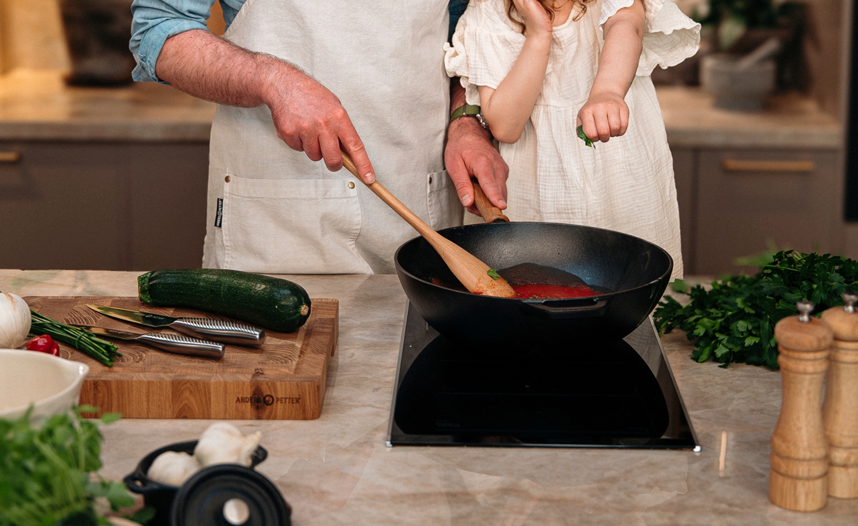 Pappa och dotter lagar mat tillsammans vid spisen i ett modernt kök med Cervera-produkter.