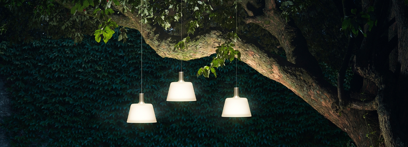 Solcellelamper i hagen som henger i et tre og lyser opp et bord