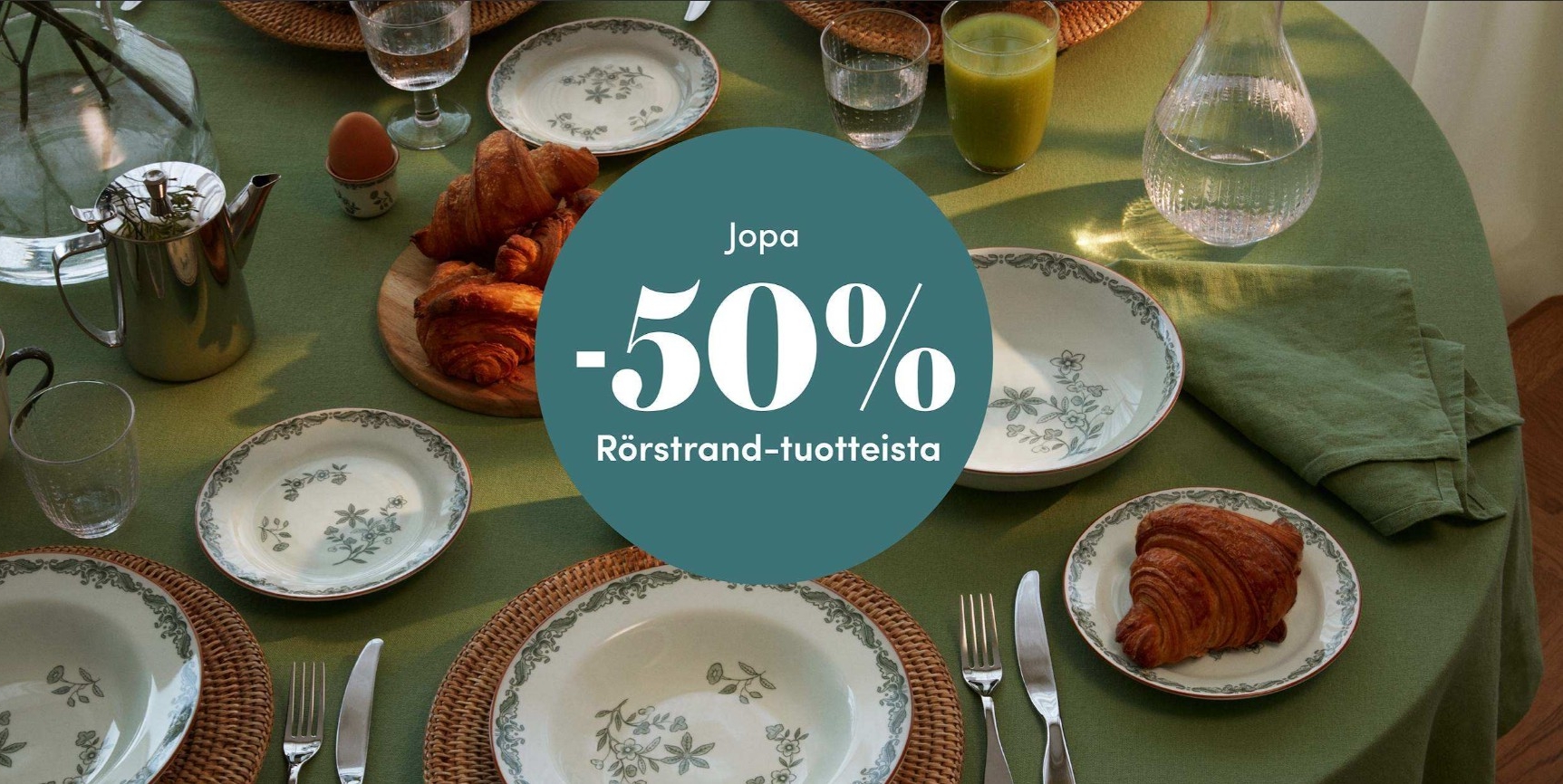 Vihreälle aamiaispöydälle katetut Rörstrand-astiat ja croissantit, jopa 50 % alennuksessa.