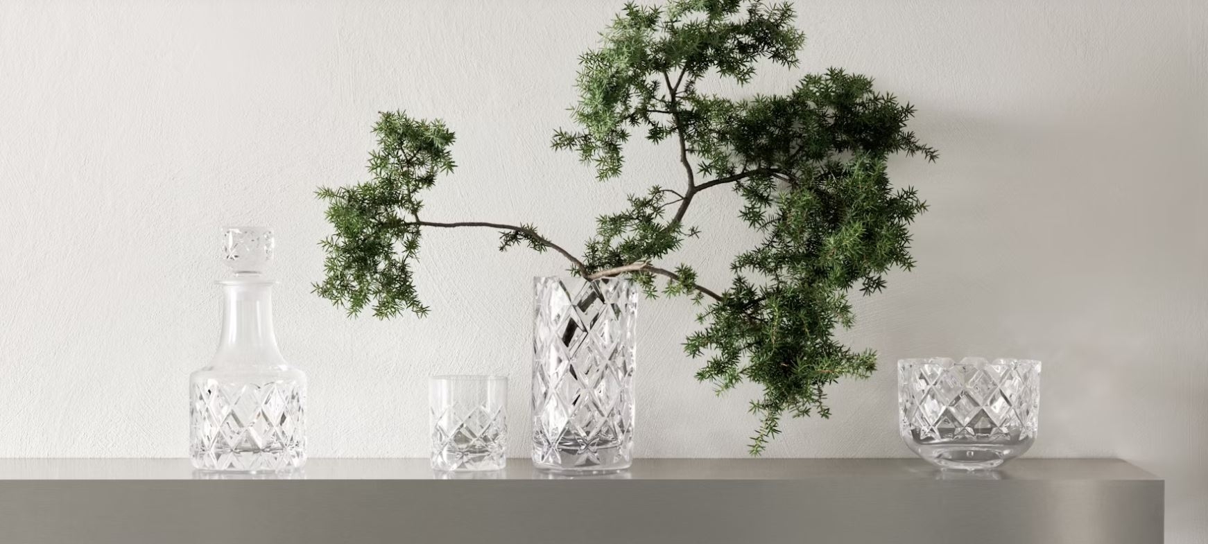 Sofiero karaffel, vase, skål og glass fra orrefors med en grønn gren i vasen
