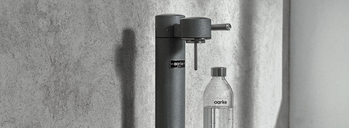 Hiilihapotuslaitte aarke vesipullo ja lasi lasihylyllä