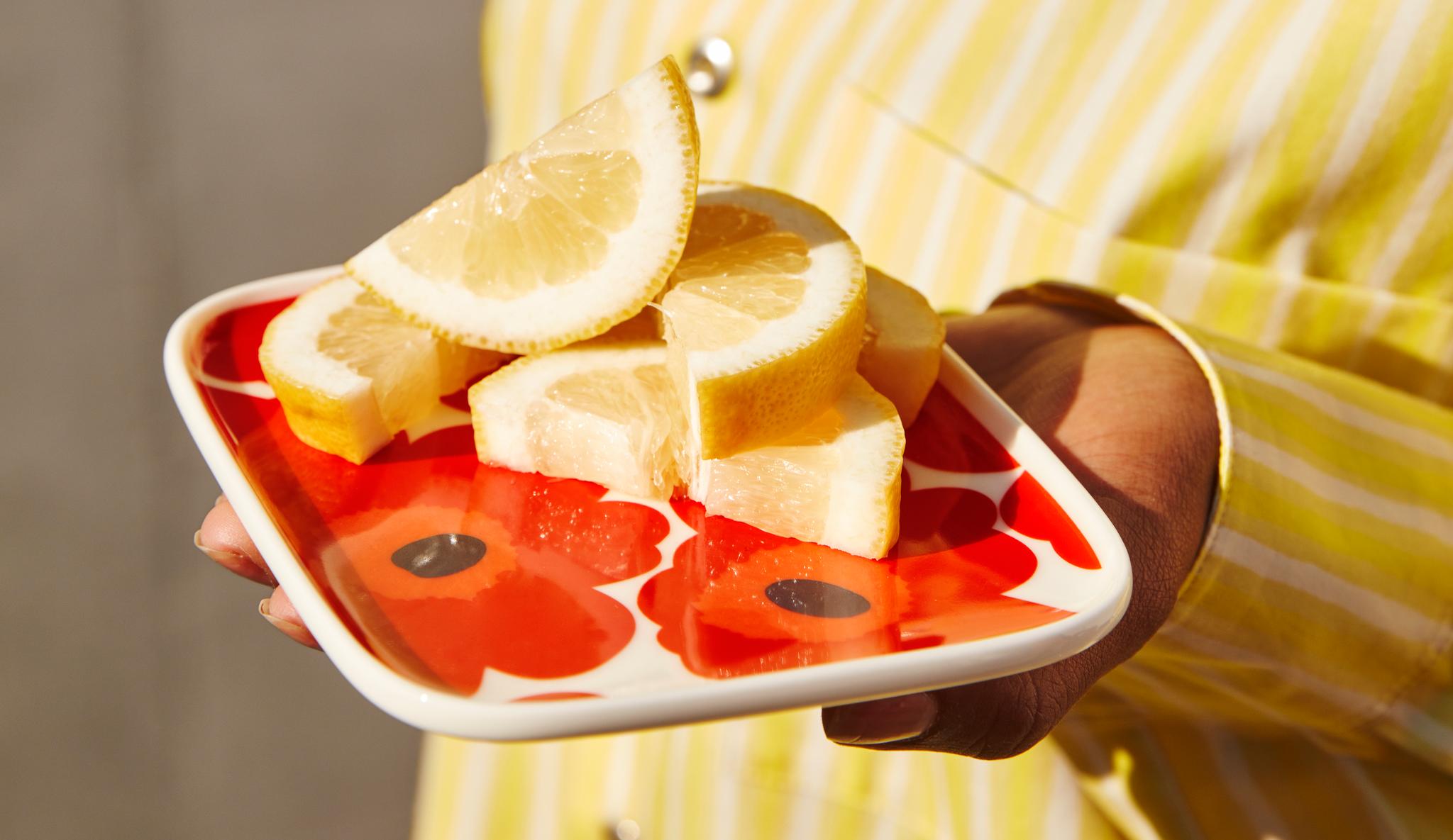 Marimekko Unikko tallerken i rødt mønster med friske sitronskiver på
