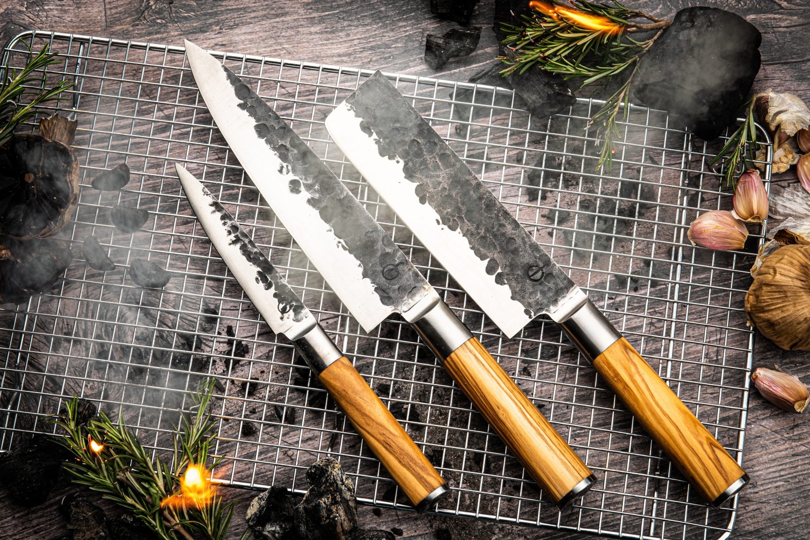 three knives with wooden handles are sitting on top of a wire rack .