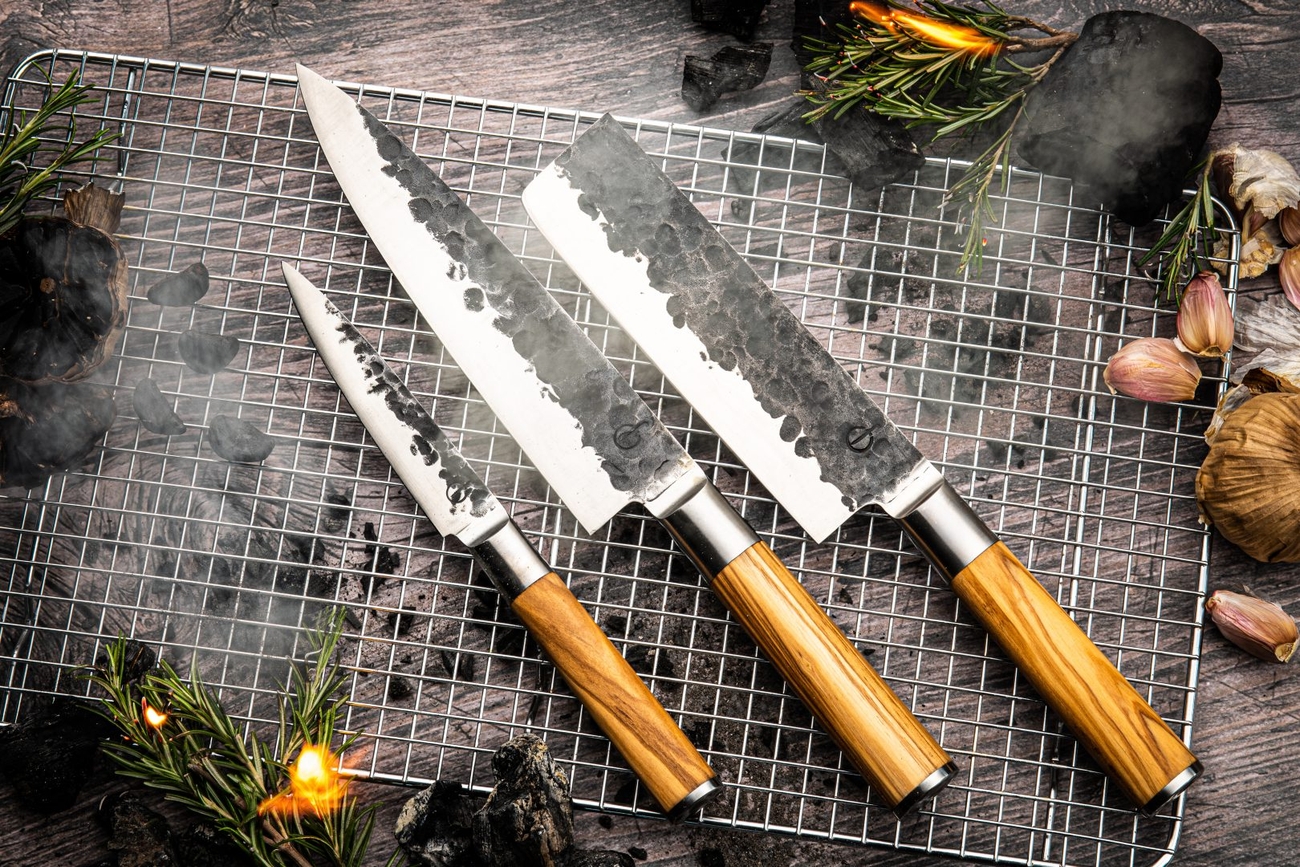 three knives with wooden handles are sitting on top of a wire rack .