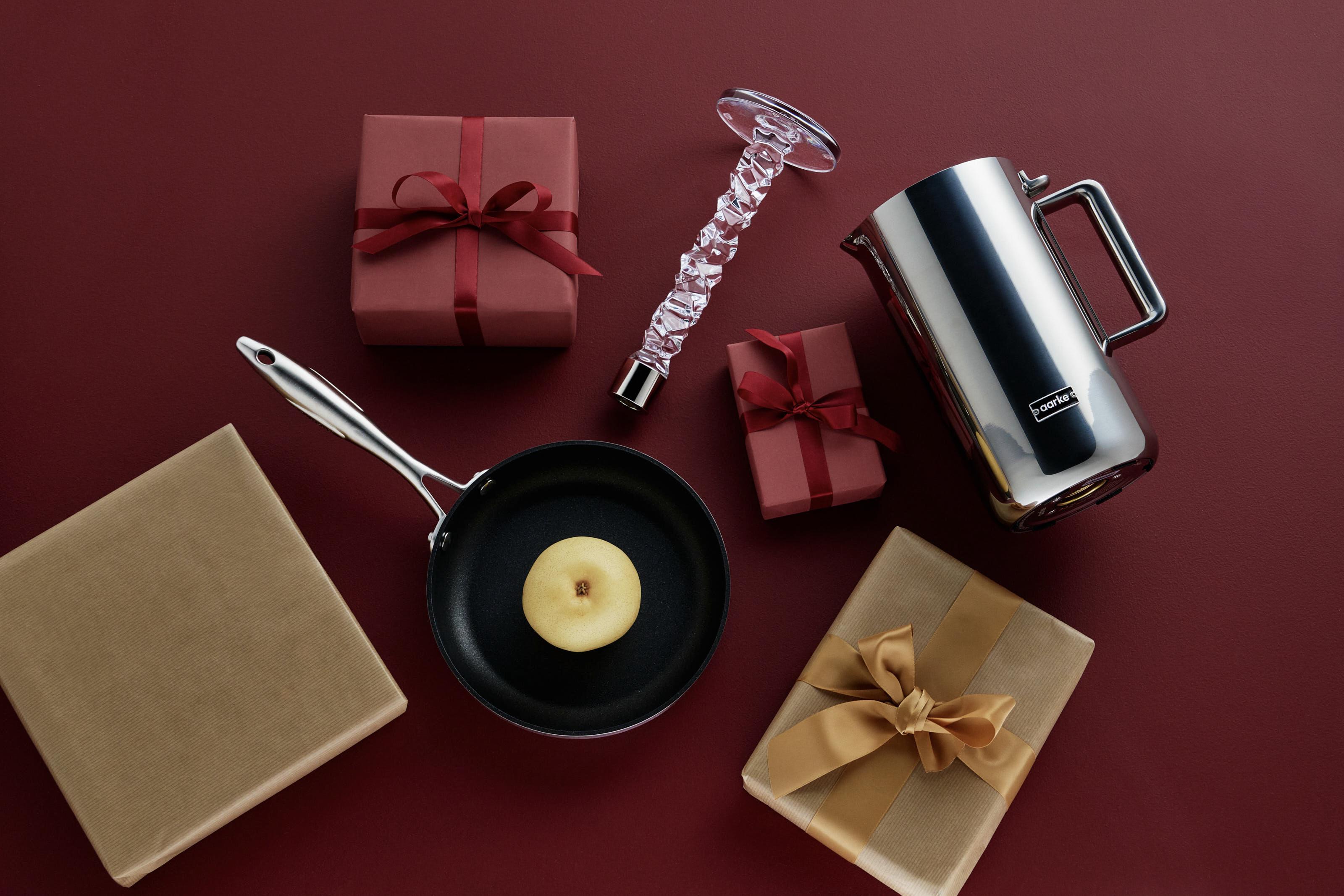 Röda inslagna julklappar, en Carat ljusstake från Orrefors och en vattenkokare från Aarke som ligger mot en röd bakgrund