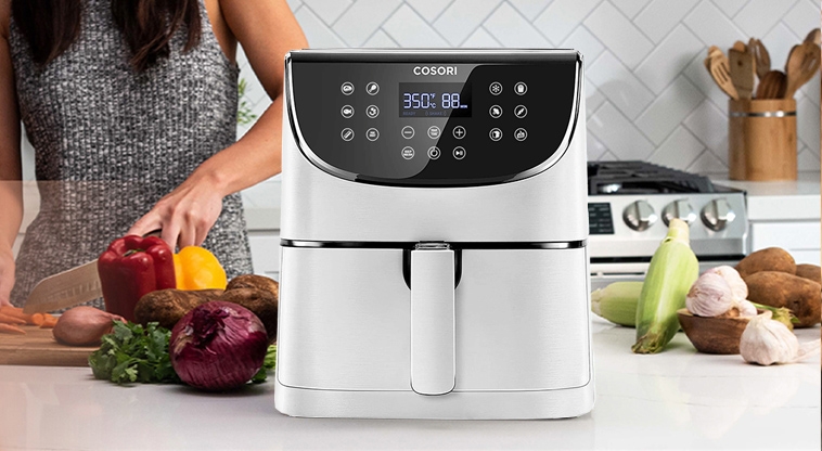 Valkoinen airfryer keittiössä ja nainen ketä pilkkoo vihanneksia
