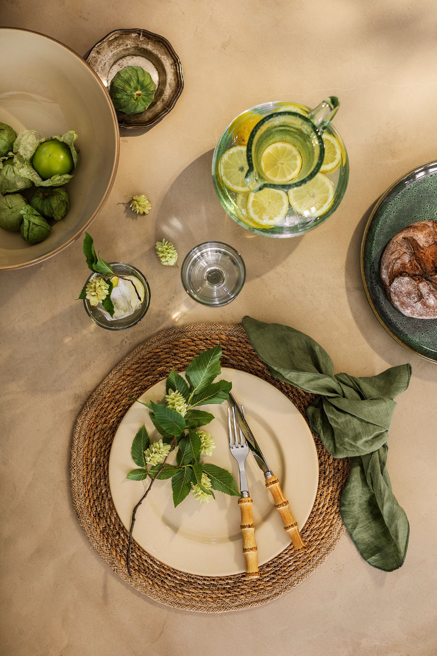 Festlig dukning i jordnära färger med beige tallrik och en grön servett på ett bordsunderlägg i jute