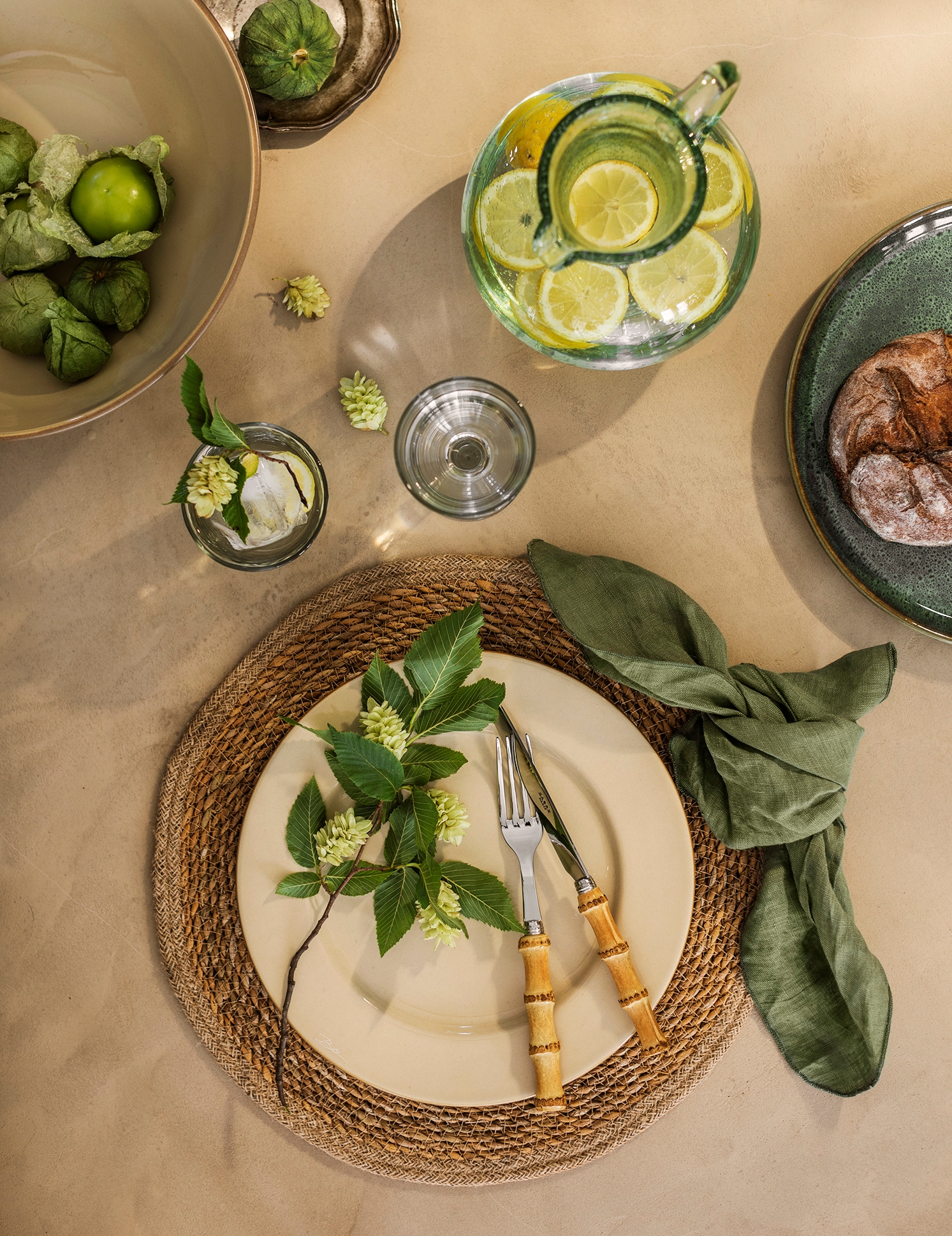 Festlig borddekking i jordfarger med beige tallerken og grønn serviett på jute dekke