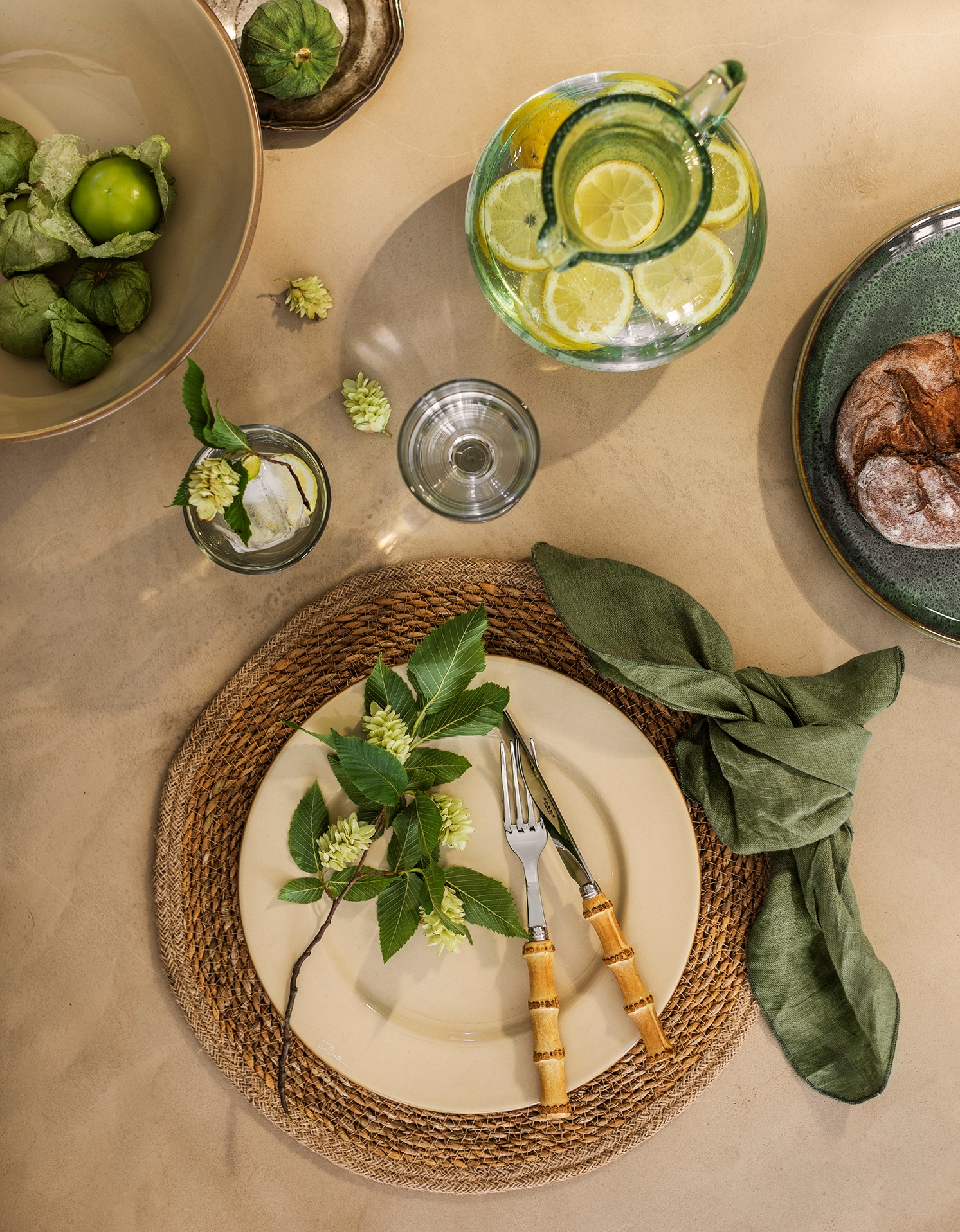 Juhlava kattaus maanläheisissä väreissä beige lautasella ja vihreällä lautasliinalla juuttimatolla