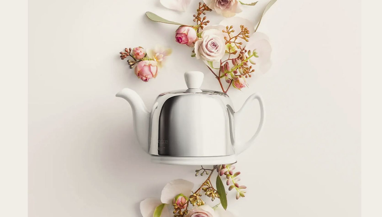 a teapot is surrounded by flowers on a table .