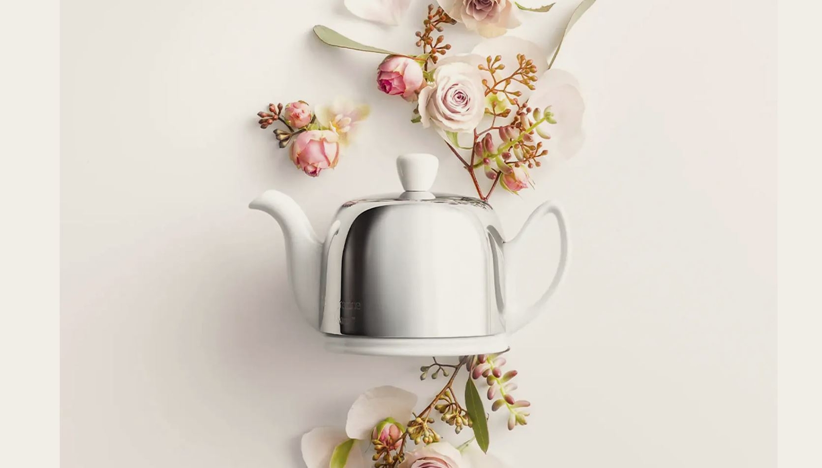 a teapot is surrounded by flowers on a table .