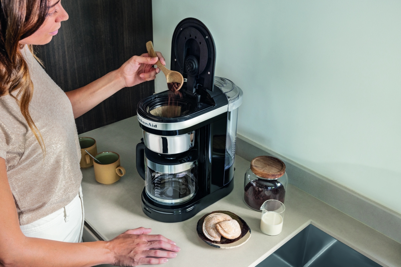 KitchenAid kaffetrakter i svart på kjøkkenet der en person heller i kaffe