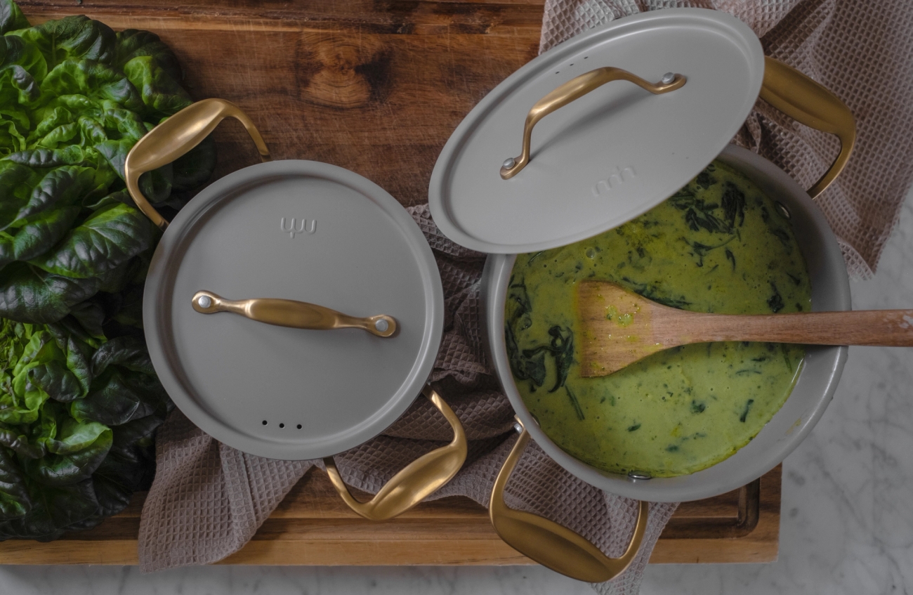 Harmaa pinnoitettu kattila kahdessa eri koossa puisella leikkuulaudalla