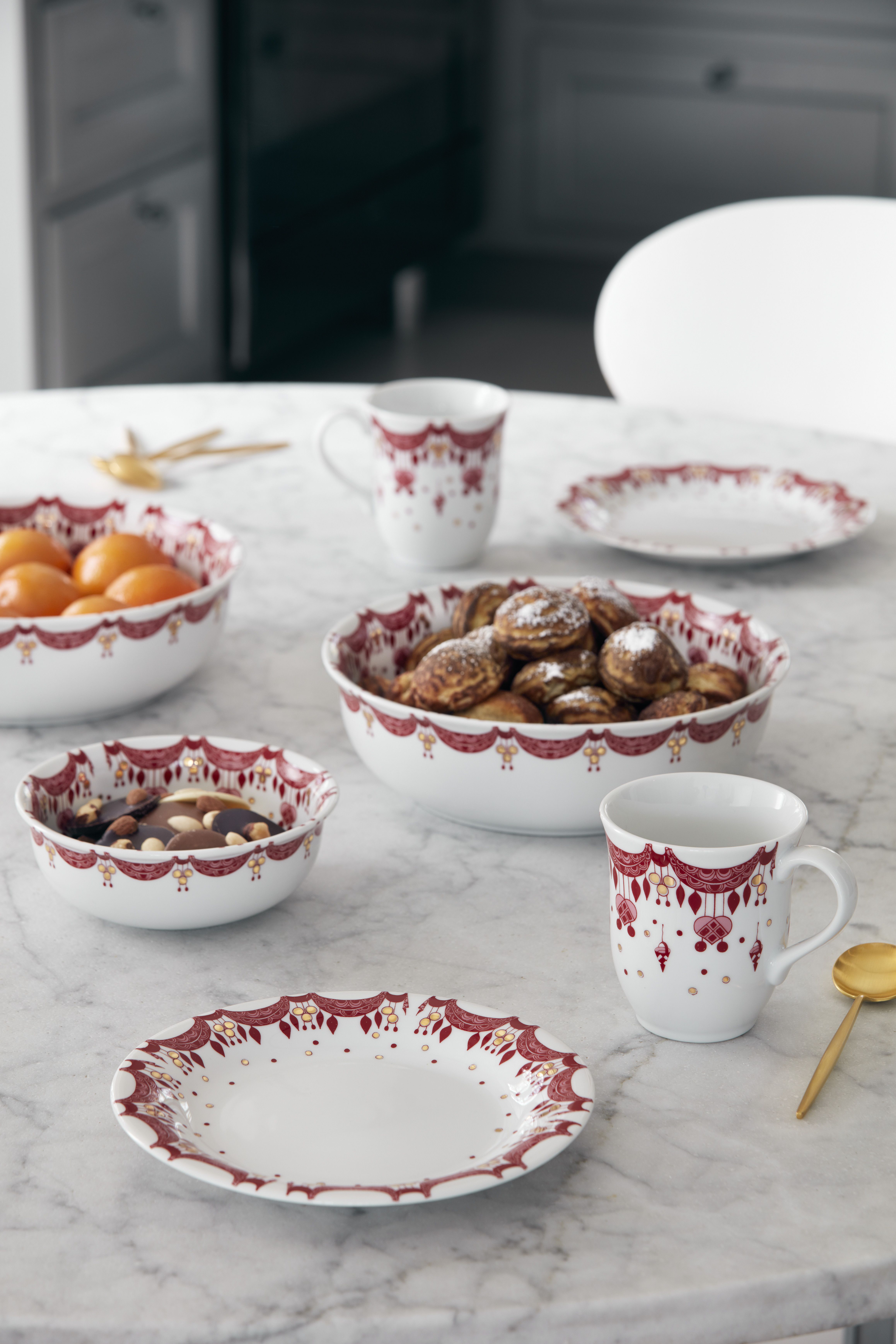 Juleborddekking med gullbestikk og hvite tallerkener med en rød julegirlander