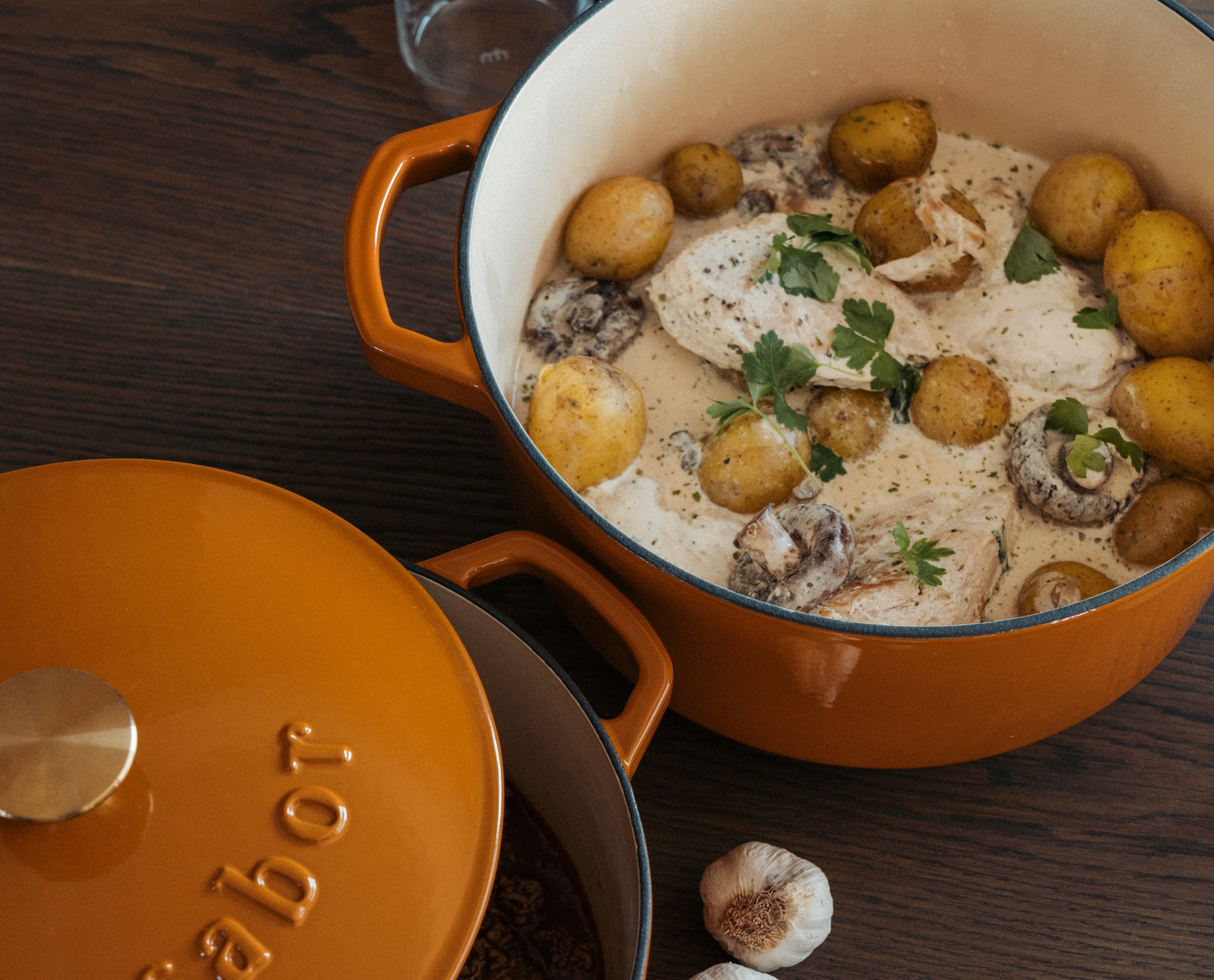 Krämig kycklinggryta med potatis, svamp och persilja serverad i en orange gjutjärnsgryta.
