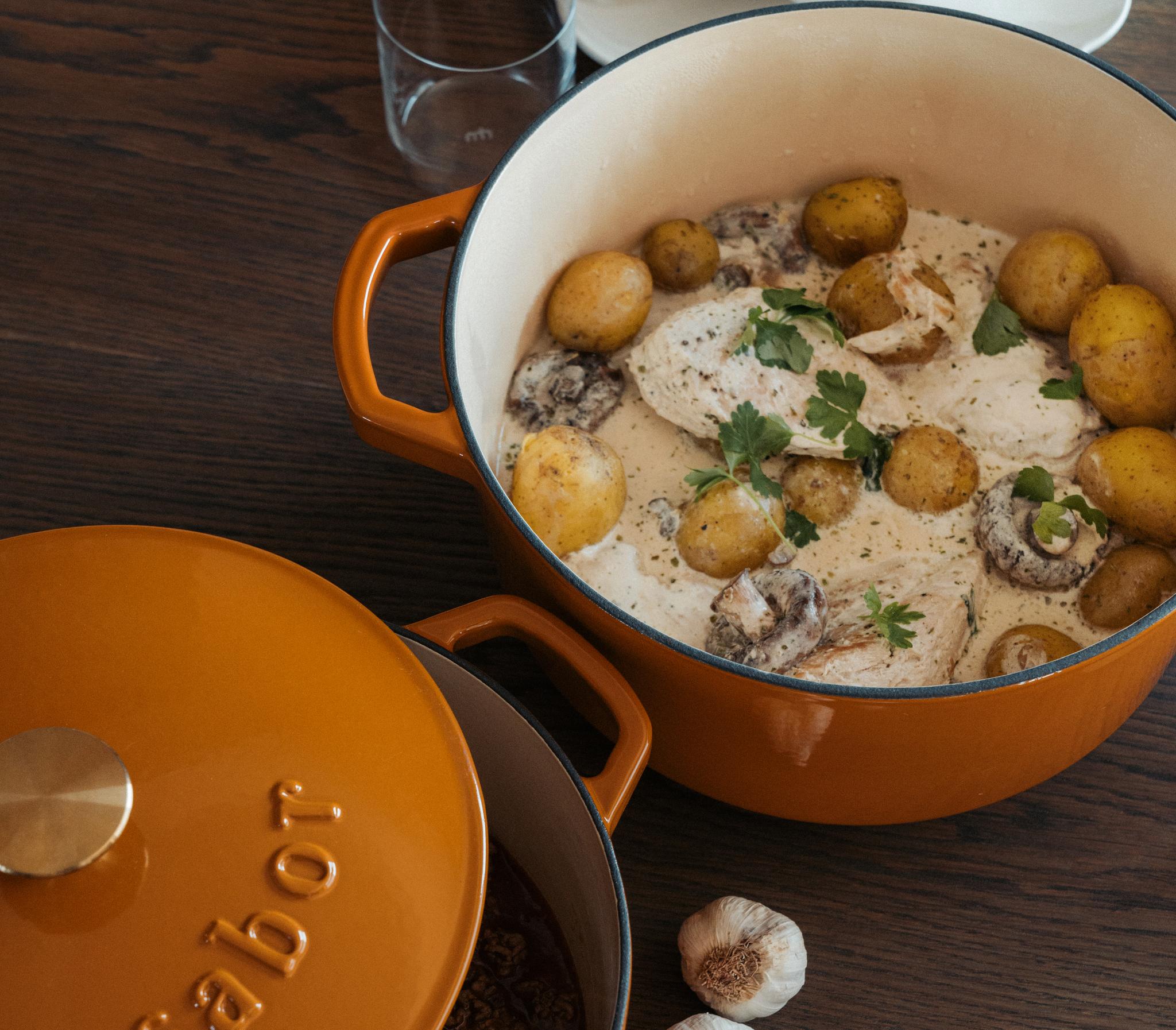 Krämig kycklinggryta med potatis, svamp och persilja serverad i en orange gjutjärnsgryta.