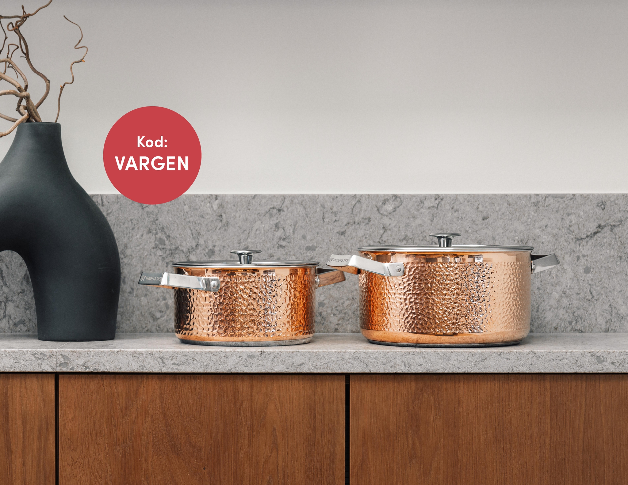 Två hamrade grytor i koppar från Vargen & Thor står på en köksbänk i marmor