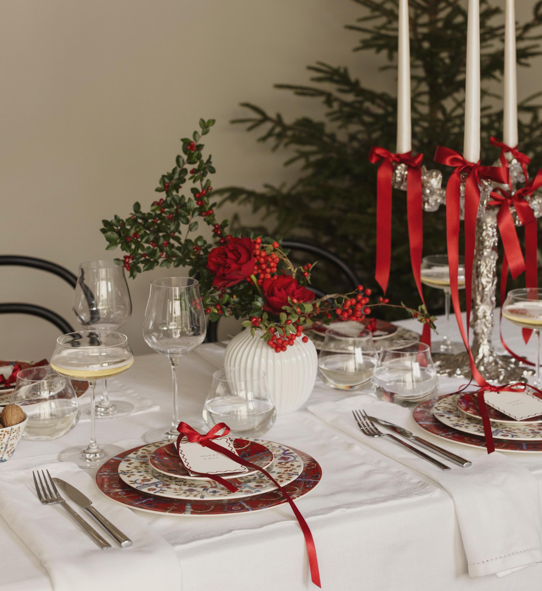 a table set for a christmas dinner with a christmas tree in the background